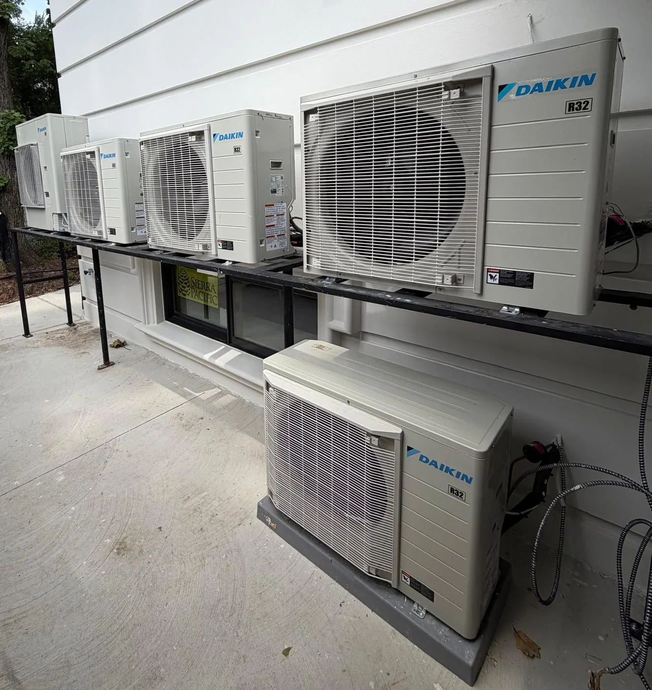 Ductless condensing units mounted on a steel wall rack beside a home