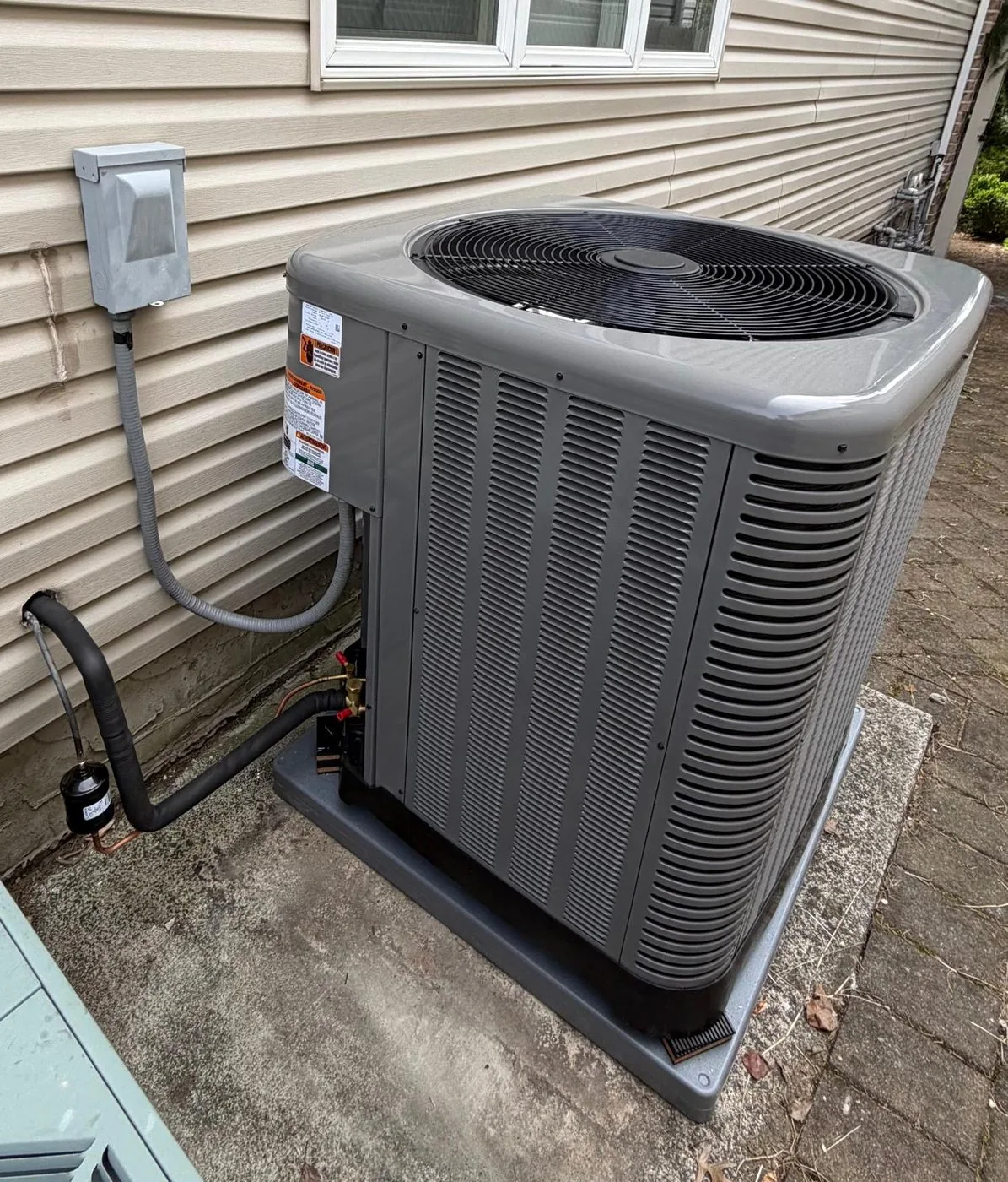 A replacement condenser on a level pad with the electrical disconnect mounted above